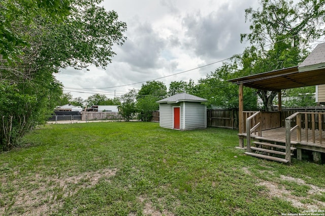 view of yard with a fenced backyard, a wooden deck, an outdoor structure, and a storage shed