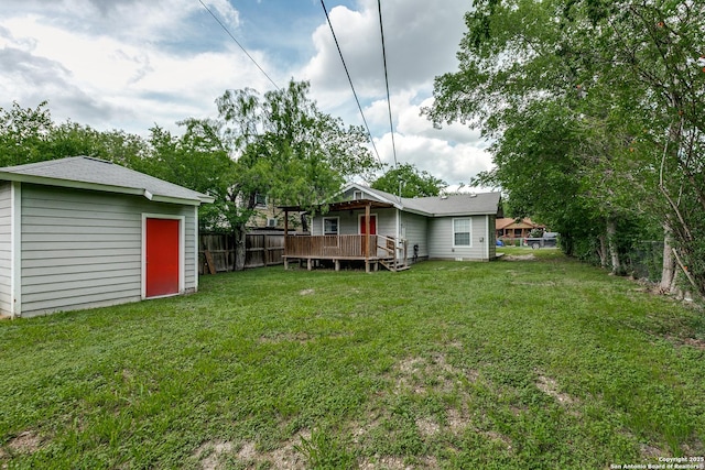 view of yard with a storage shed, a deck, fence, and an outbuilding