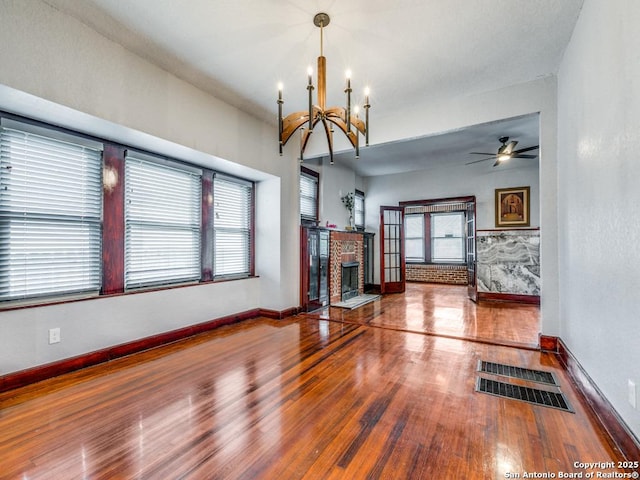 1520 Virginia, San Antonio, TX 78203 - unfurnished living room with a brick fireplace, ceiling fan with notable chandelier, baseboards, wood finished floors, and visible vents