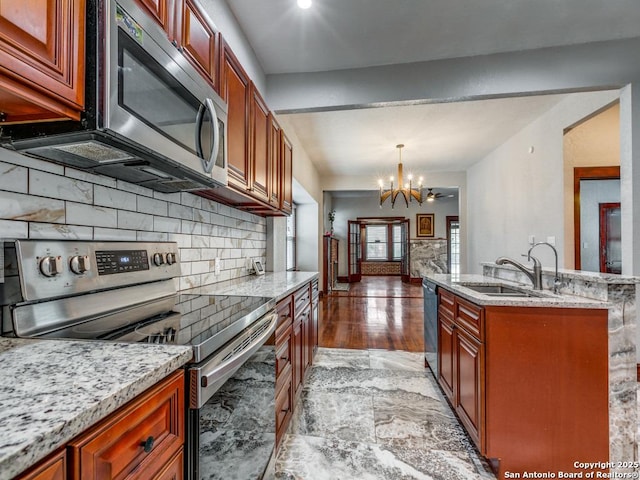 1520 Virginia, San Antonio, TX 78203 - kitchen featuring light stone countertops, a notable chandelier, appliances with stainless steel finishes, a sink, and decorative backsplash