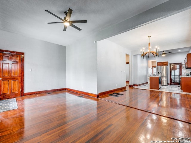 1520 Virginia, San Antonio, TX 78203 - unfurnished living room with baseboards, light wood-style flooring, and ceiling fan with notable chandelier