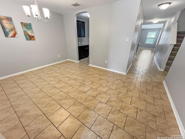 unfurnished room featuring visible vents, arched walkways, baseboards, an inviting chandelier, and light tile patterned flooring