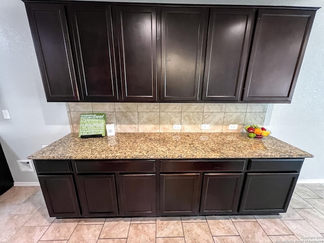 kitchen featuring baseboards, light stone countertops, and decorative backsplash