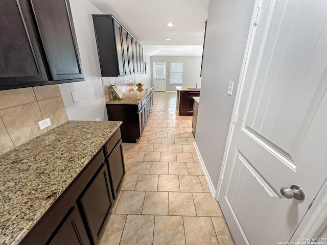 corridor with baseboards, recessed lighting, and a sink
