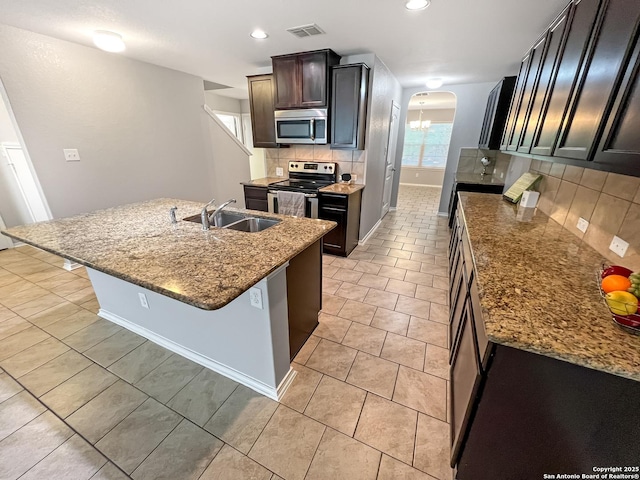 kitchen featuring a sink, arched walkways, stainless steel appliances, tasteful backsplash, and visible vents