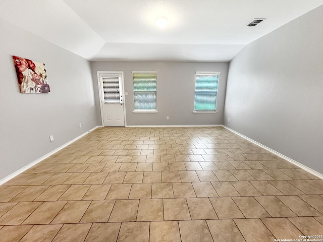foyer entrance featuring light tile patterned flooring, baseboards, visible vents, and lofted ceiling