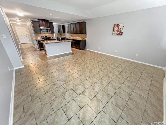 kitchen with baseboards, open floor plan, recessed lighting, tasteful backsplash, and appliances with stainless steel finishes