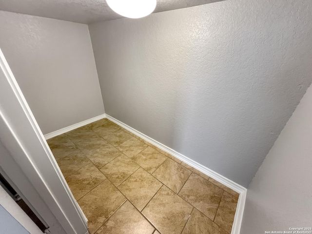 interior space featuring light tile patterned floors, baseboards, and a textured ceiling