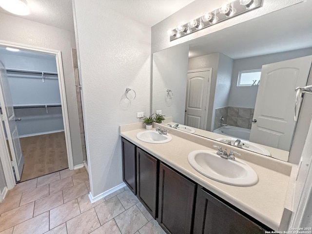 full bathroom with double vanity, a walk in closet, a sink, and a bath