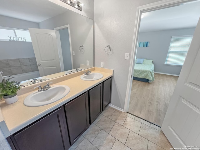 ensuite bathroom with double vanity, baseboards, a sink, and ensuite bathroom