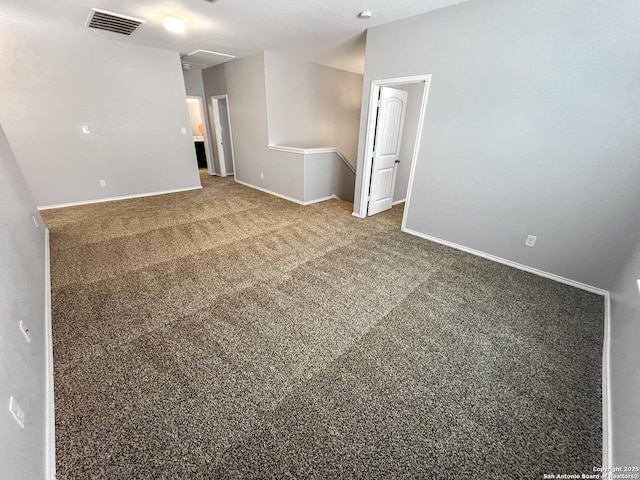 carpeted empty room featuring visible vents, attic access, and baseboards