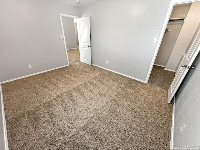 unfurnished bedroom with carpet floors, baseboards, and a spacious closet