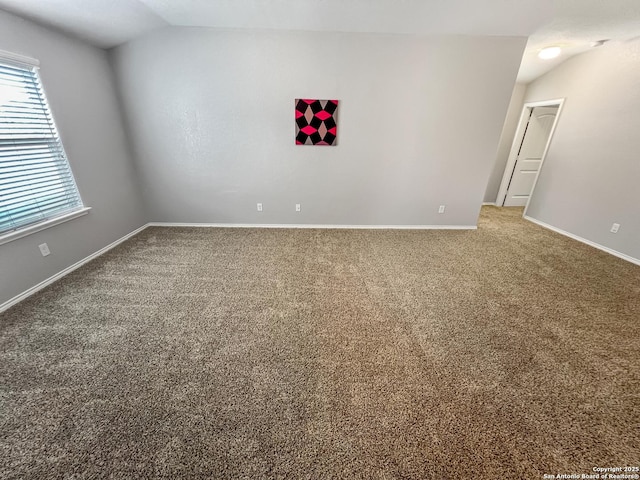unfurnished room featuring baseboards, carpet, and vaulted ceiling