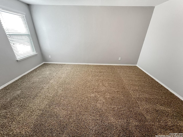 carpeted empty room featuring baseboards