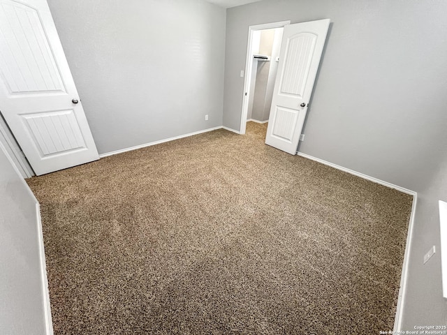 unfurnished bedroom with baseboards, carpet, and a spacious closet