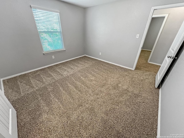 empty room featuring baseboards and carpet