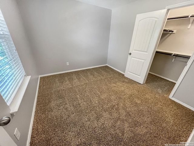 unfurnished bedroom featuring carpet floors, baseboards, a closet, and a spacious closet