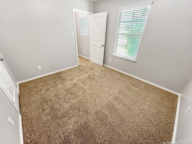 spare room featuring baseboards and carpet