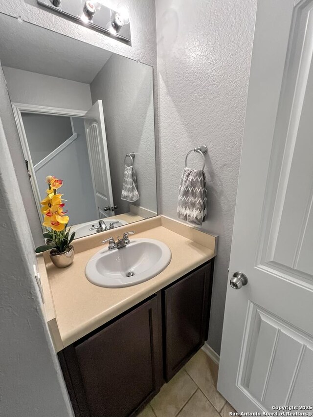 bathroom with vanity, a textured wall, and tile patterned floors