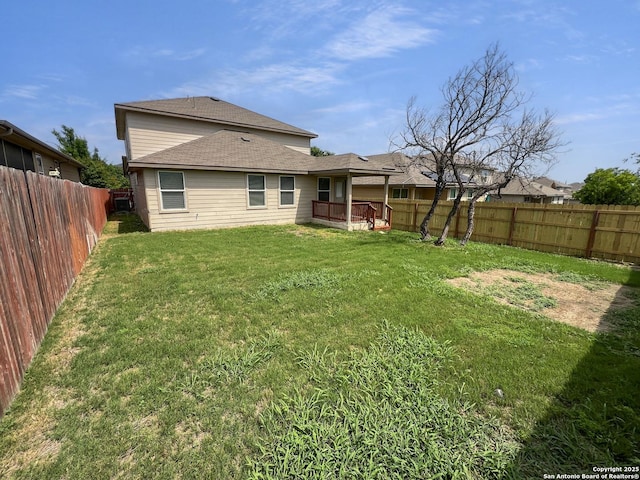 back of house with a yard, a fenced backyard, and roof with shingles