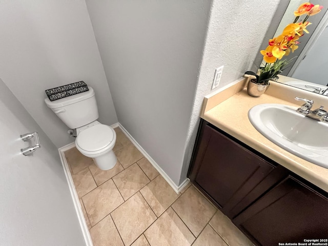 half bathroom featuring vanity, tile patterned flooring, and toilet