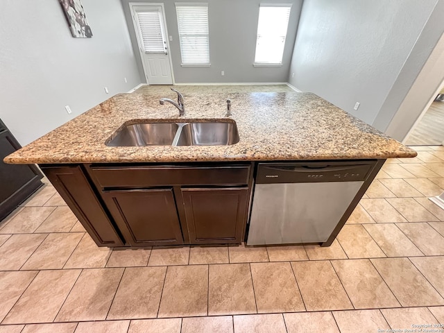 kitchen featuring light stone counters, a sink, dishwasher, a kitchen island with sink, and light tile patterned floors