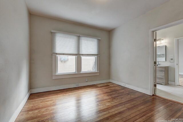 1932 W Huisache, San Antonio, TX 78201 - unfurnished bedroom featuring baseboards, connected bathroom, and hardwood / wood-style flooring