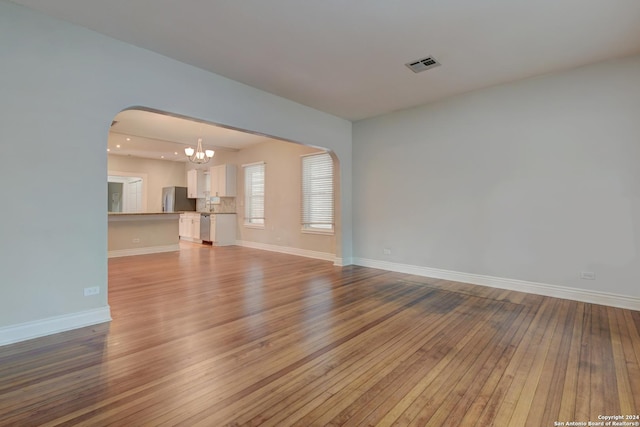 1932 W Huisache, San Antonio, TX 78201 - unfurnished room with visible vents, arched walkways, baseboards, an inviting chandelier, and hardwood / wood-style floors