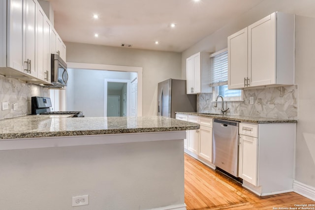 1932 W Huisache, San Antonio, TX 78201 - kitchen featuring white cabinets, light stone counters, appliances with stainless steel finishes, a sink, and light wood-type flooring