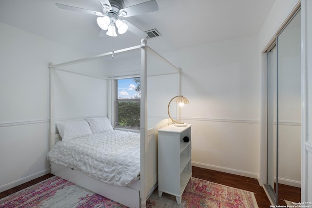 bedroom featuring visible vents, a closet, wood finished floors, baseboards, and a ceiling fan