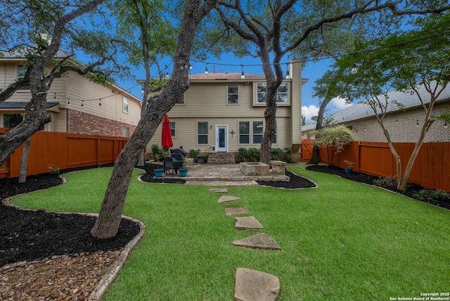 rear view of house with a patio, a fenced backyard, a lawn, and a chimney