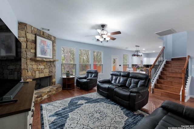 living room featuring stairs, a ceiling fan, visible vents, and wood finished floors