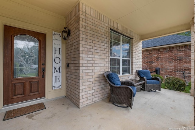 entrance to property featuring covered porch and brick siding