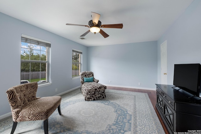 sitting room with ceiling fan, visible vents, baseboards, and wood finished floors