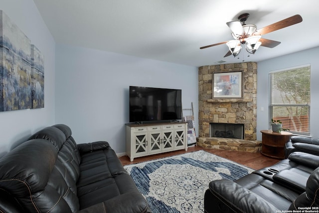 living area featuring baseboards, ceiling fan, wood finished floors, and a fireplace