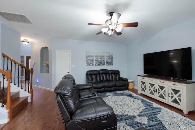 living room with dark wood-style flooring, ceiling fan, baseboards, visible vents, and stairway