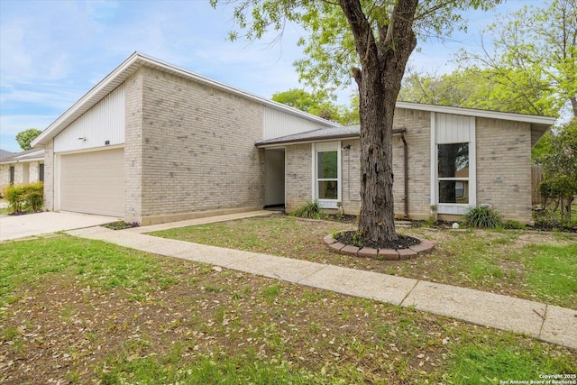 mid-century modern home featuring a garage, concrete driveway, and brick siding