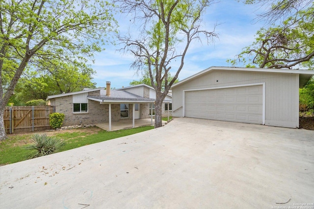 ranch-style home featuring fence, a chimney, concrete driveway, and a garage