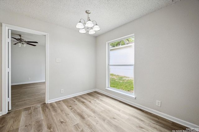 spare room with baseboards, a textured ceiling, light wood finished floors, and a chandelier