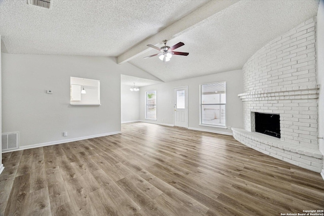 unfurnished living room featuring a textured ceiling, visible vents, a fireplace, ceiling fan with notable chandelier, and vaulted ceiling with beams