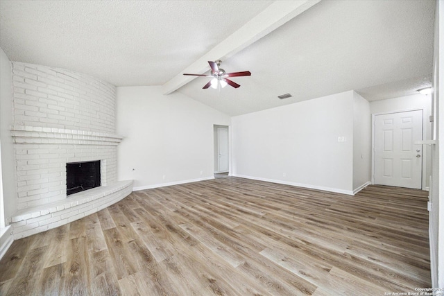 unfurnished living room featuring visible vents, wood finished floors, ceiling fan, vaulted ceiling with beams, and a textured ceiling