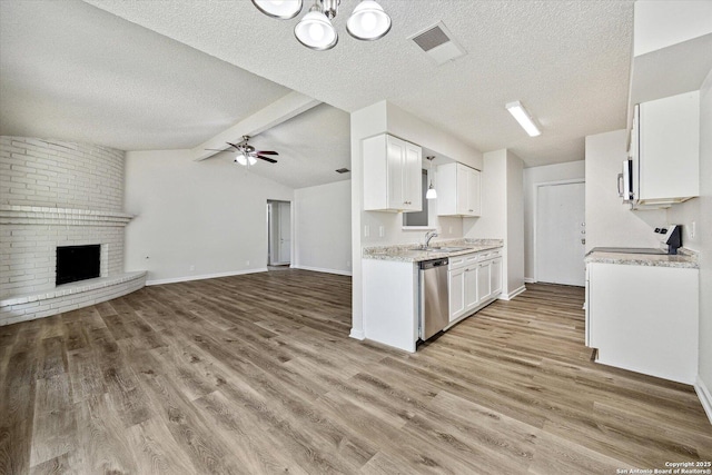 kitchen featuring appliances with stainless steel finishes, light wood-type flooring, a sink, white cabinets, and open floor plan