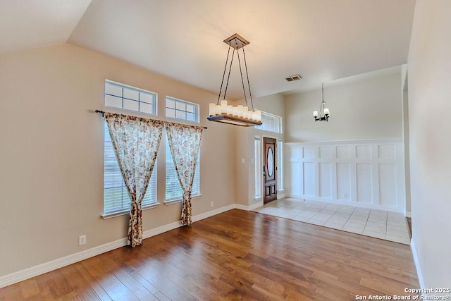 26923 Trinity Hts, San Antonio, TX 78261 - unfurnished dining area featuring vaulted ceiling, wood-type flooring, a notable chandelier, and visible vents