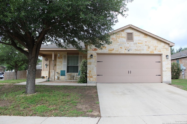 view of front of house with fence, an attached garage, stone siding, a porch, and driveway
