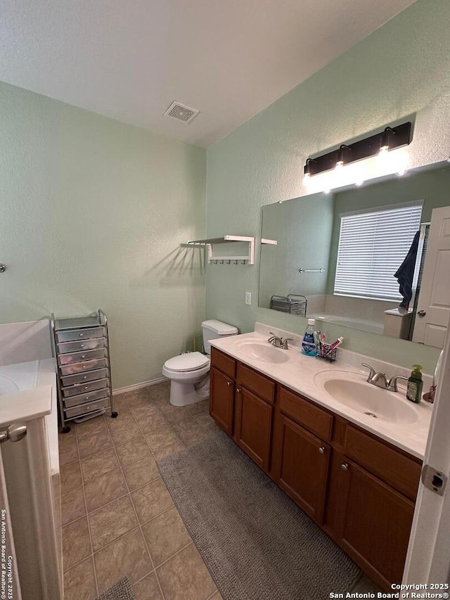 full bath featuring visible vents, a sink, a textured wall, and double vanity