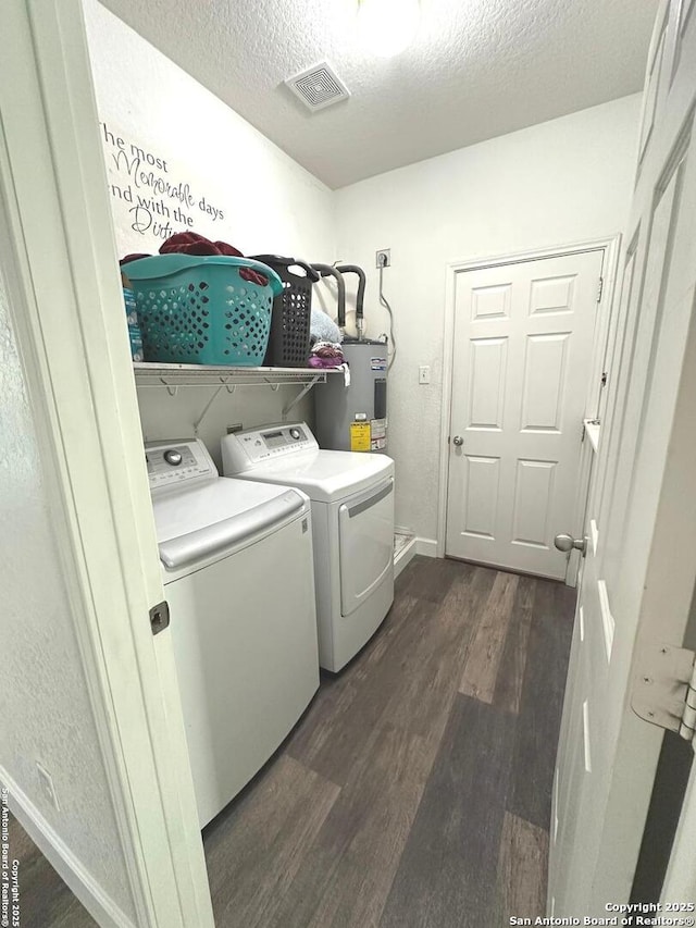 laundry area with washing machine and clothes dryer, laundry area, water heater, dark wood-type flooring, and visible vents