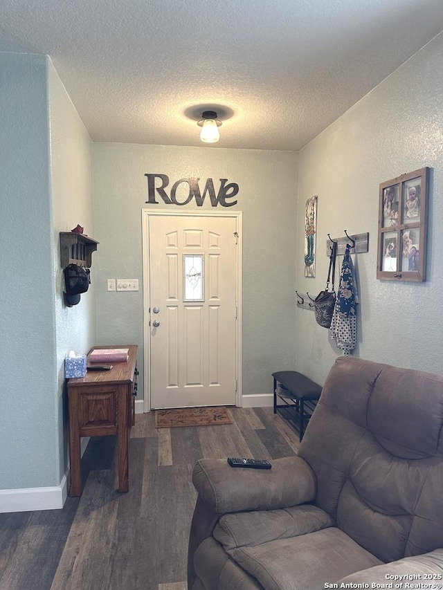 interior space featuring baseboards, a textured ceiling, a textured wall, and wood finished floors