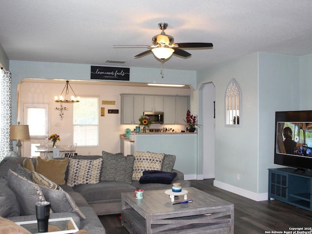 living area with dark wood-style flooring, arched walkways, baseboards, and ceiling fan with notable chandelier