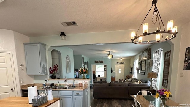 kitchen featuring a sink, visible vents, ceiling fan with notable chandelier, gray cabinetry, and dark wood-style floors