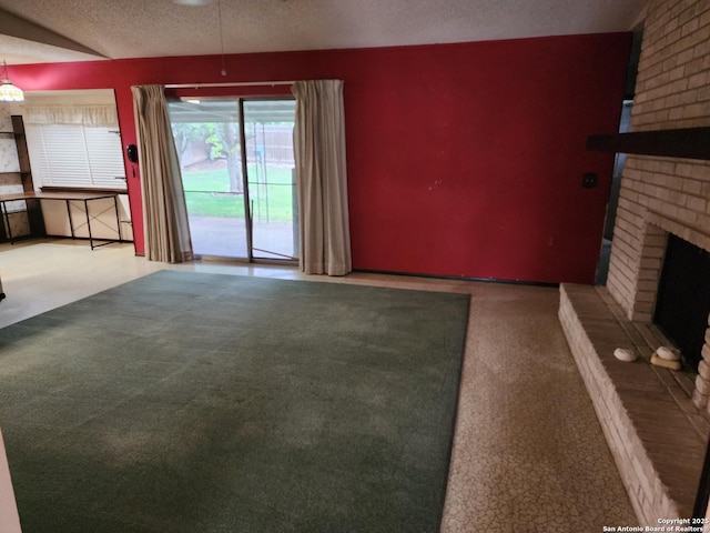 unfurnished living room with carpet floors, ceiling fan, a brick fireplace, and a textured ceiling